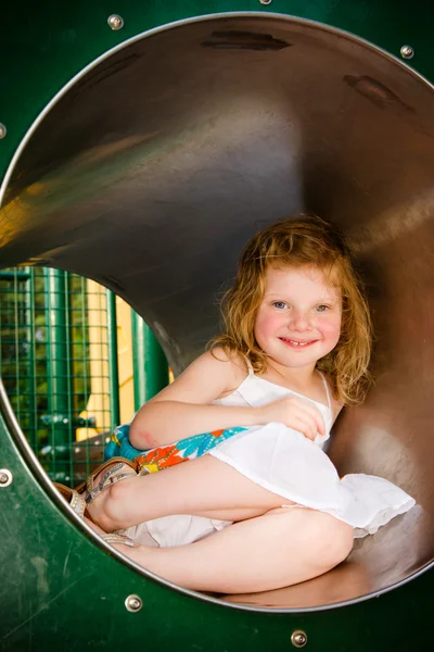 Милая маленькая девочка играет в тоннеле на детской площадке — стоковое фото