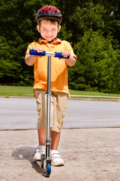 Criança montando scooter ao ar livre para o exercício — Fotografia de Stock
