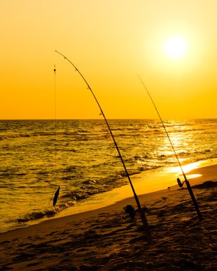 gün batımında beach kıyıda balıkçılık çubuklar kurmak