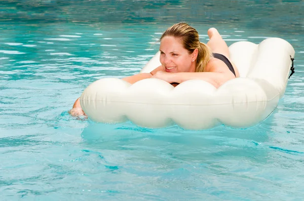 Mulher de meia-idade feliz flutuando na jangada na piscina — Fotografia de Stock