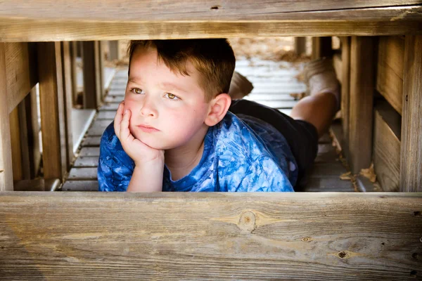 Niño infeliz escondido y enfurruñado mientras juega en el patio de recreo —  Fotos de Stock