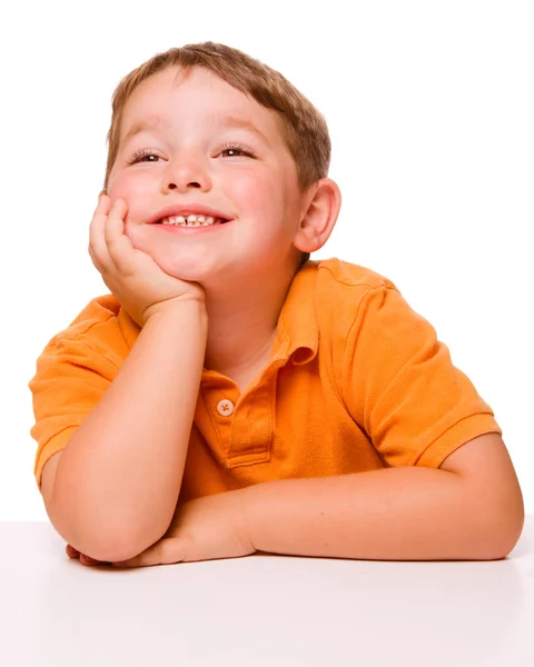 Glückliches aufmerksames Kind, das am Schreibtisch sitzt und zuhört — Stockfoto