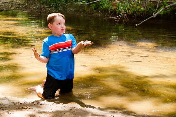 Niño jugando en el barro en el arroyo forestal —  Fotos de Stock
