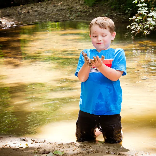 Dítě hrající v blátě v lesní potok — Stock fotografie