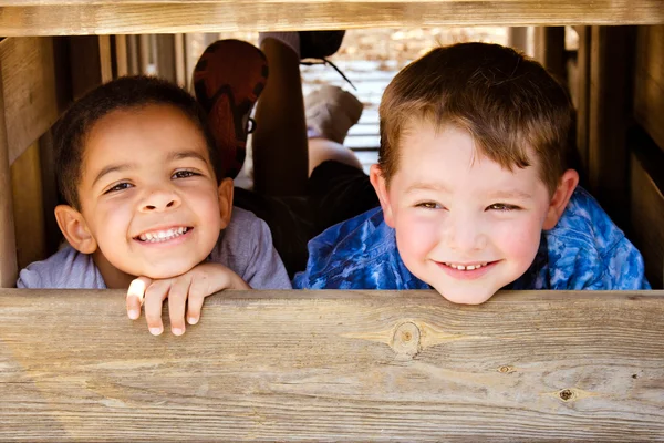 African-American child and caucasian child playing together on playground Stock Image