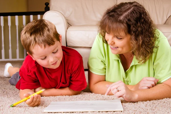 Mãe ajudando a criança com a lição de escrita para a escola em casa — Fotografia de Stock