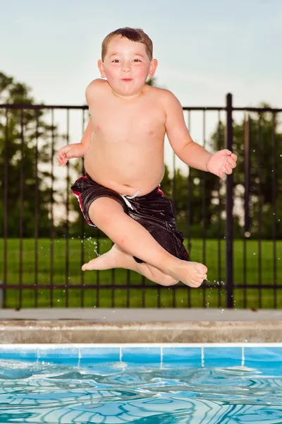 Criança pulando na piscina enquanto vai nadar durante o verão — Fotografia de Stock