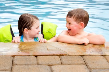 Children playing together laughing and smiling while swimming in pool