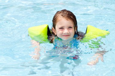 Young girl swimming in pool during hot day in summer