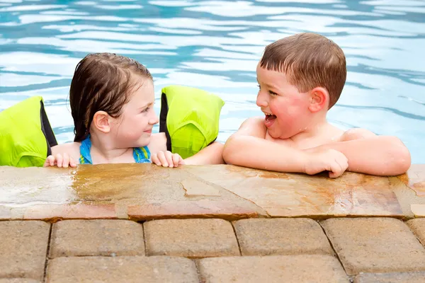 Niños jugando juntos riendo y sonriendo mientras nadan en la piscina — Foto de Stock
