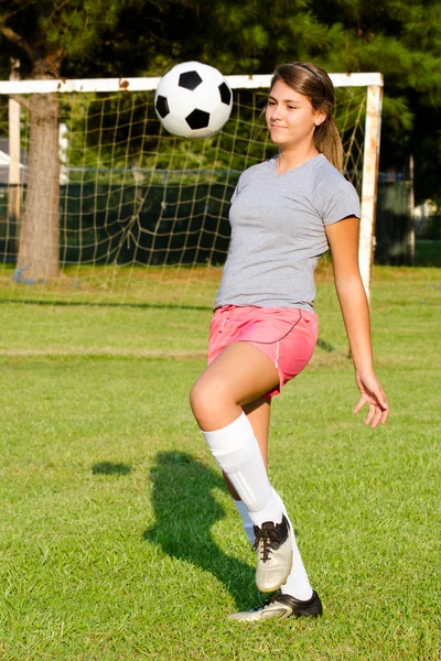 Adolescente menina malabarismo bola de futebol com os joelhos — Fotografia de Stock