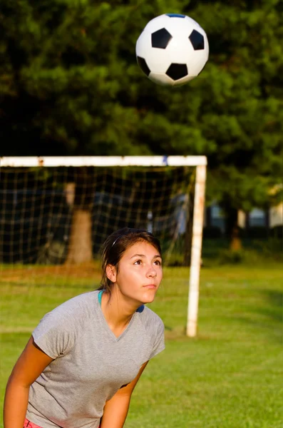 Dospívající dívka nadpis fotbalový míč při hraní na hřišti — Stock fotografie