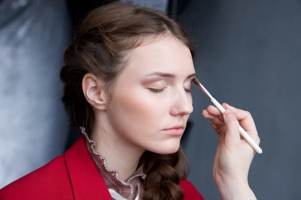 Pretty young woman having powder applied by a make-up artist Stock Photo