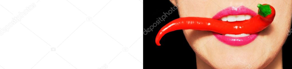 Beautiful woman teeth eating red hot chili pepper