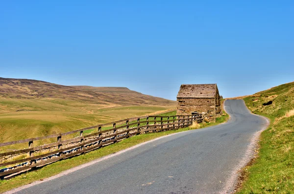 Country road and old stone barn — Stock Photo, Image