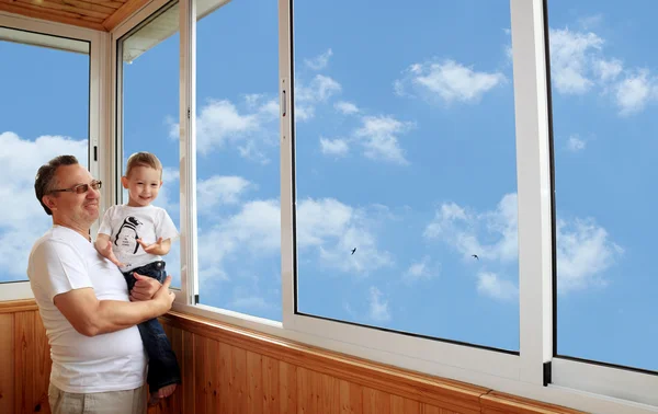Grandson and grandfather standing on balcony and looking at the — Stock Photo, Image
