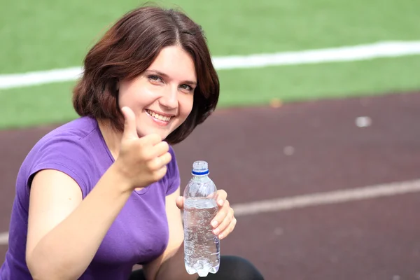 Nádherné fitness žena s lahví vody a palec nahoru — Stock fotografie