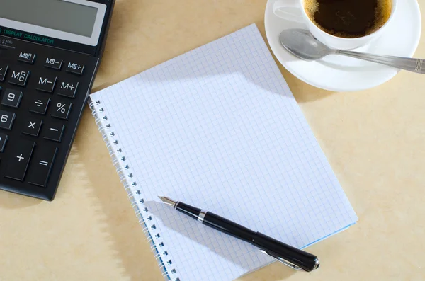 Kaffee, Taschenrechner und Notizbuch auf dem Schreibtisch — Stockfoto