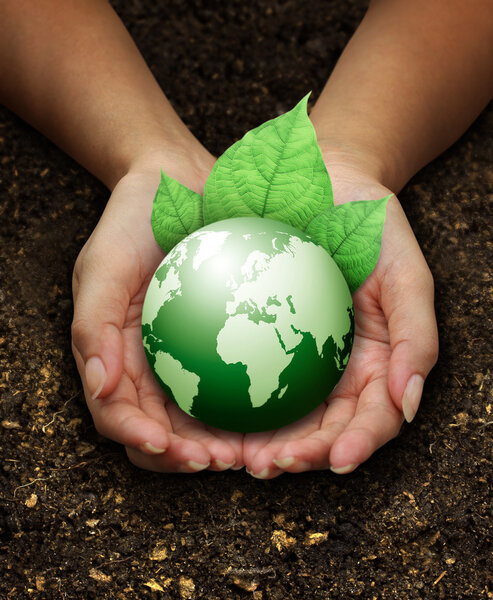 Human hands holding green earth with a leaf on soil
