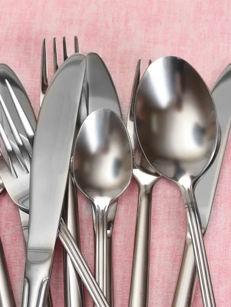 Forchette, cucchiai e coltelli su una tovaglia rosa primo piano — Foto Stock