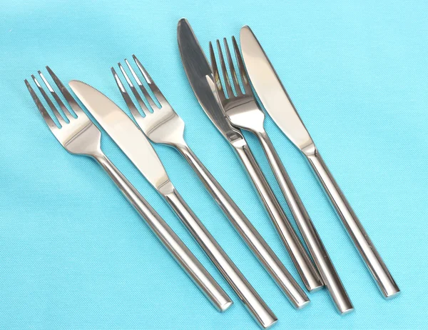 Forks and knives on a blue tablecloth — Stock Photo, Image