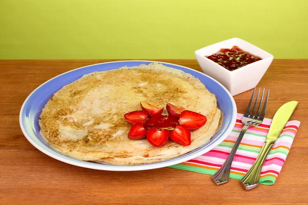 Stack of tasty pancakes on wooden table on green background — Stock Photo, Image
