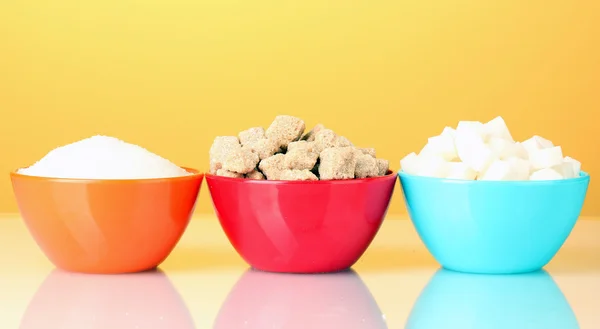 Colorful bowls with different types of sugar on a bright background — Zdjęcie stockowe