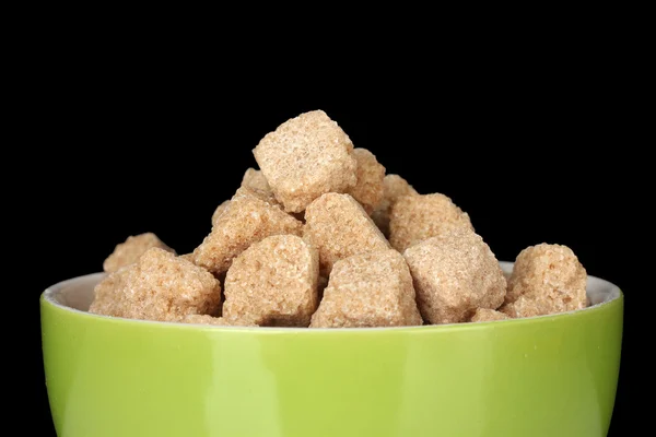 Brown cane sugar cubes in bowl on black background — Stock Photo, Image