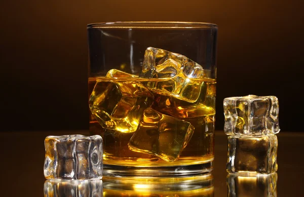 ウイスキーと茶色の背景に氷のグラス — ストック写真