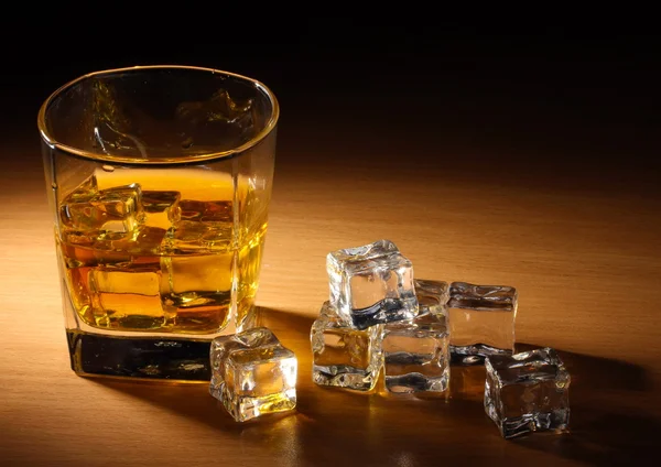 Sklo skotské whisky a ledu na dřevěný stůl — Stock fotografie