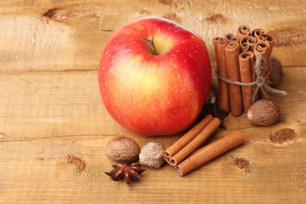 Bâtonnets de cannelle, pomme rouge, muscade et anis sur table en bois — Photo