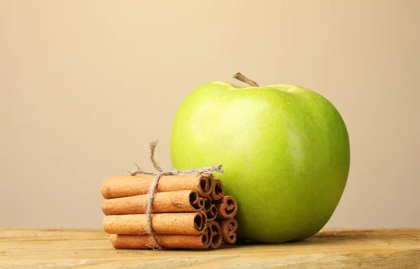 Bastoncini di cannella e mela verde su tavolo di legno su sfondo marrone — Foto Stock