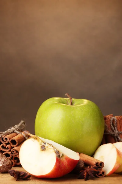 Bâtonnets de cannelle, pommes noix de muscade et anis sur table en bois sur fond brun — Photo