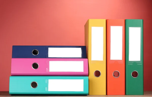 Bright office folders on wooden table on red background — Stock Photo, Image