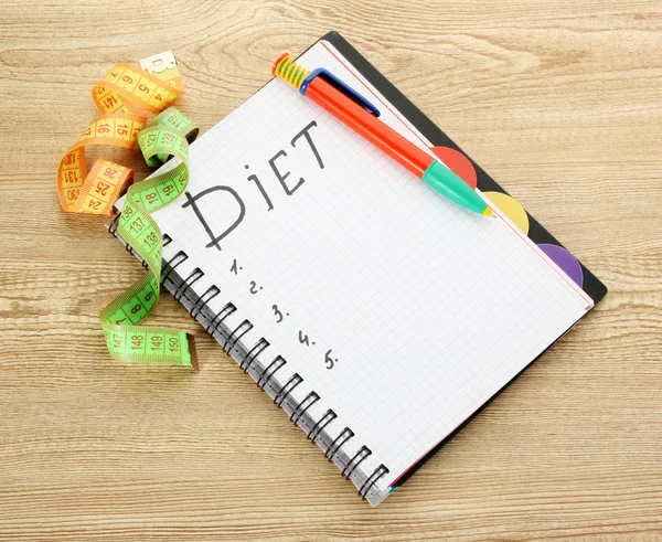 Planning of diet. Notebook measuring tapes and pen on wooden table — Stock Photo, Image
