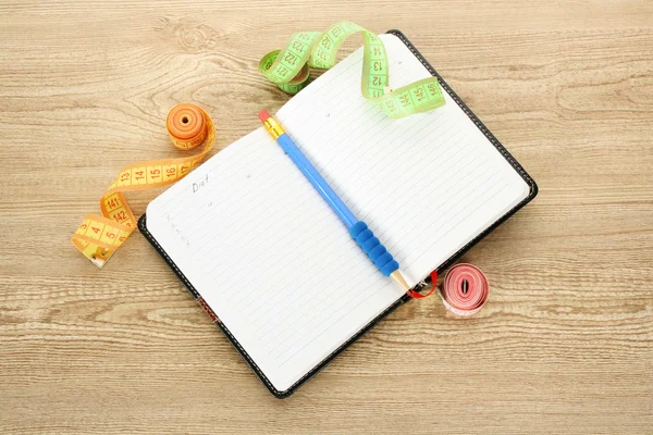 Planowania diety. taśmy pomiarowe notatnik i długopis na drewnianym stole — Zdjęcie stockowe