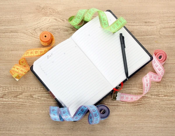 Planning van dieet. meten tapes van de notebook en pen op houten tafel — Stockfoto