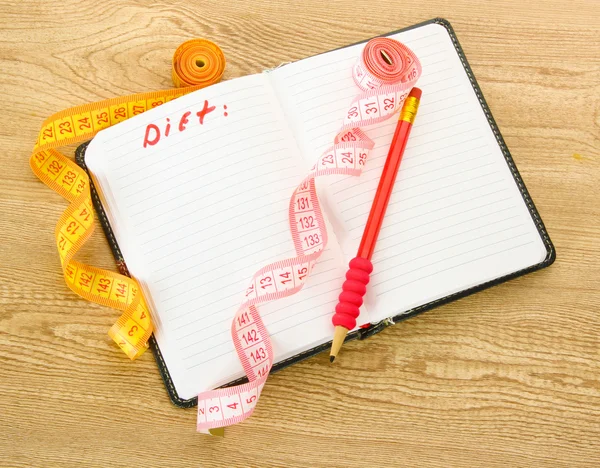 Planificación de la dieta. Cintas métricas para cuadernos y bolígrafo sobre mesa de madera — Foto de Stock