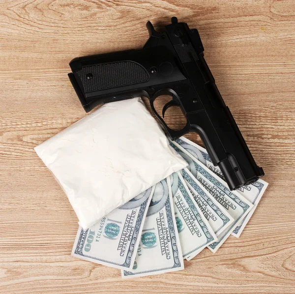 Kokain i paketet, dollar och pistol på trä bakgrund — Stockfoto