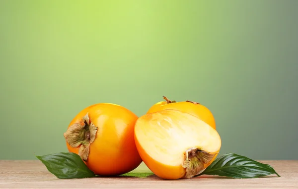 Iştah açıcı persimmons yeşil zemin üzerine ahşap tablo — Stok fotoğraf