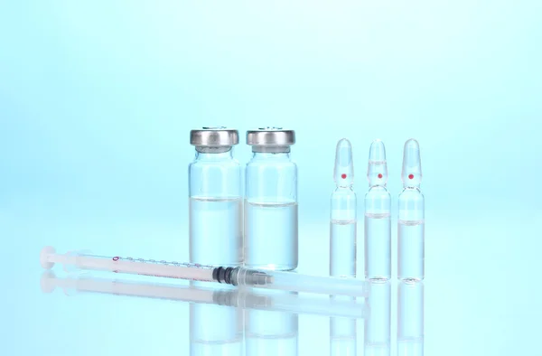 Syringe and medical ampoules on blue background — Stock Photo, Image
