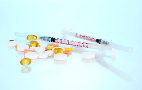 Inzulinové stříkačky s lékařskou ampulí a tablety na modrém pozadí — Stock fotografie