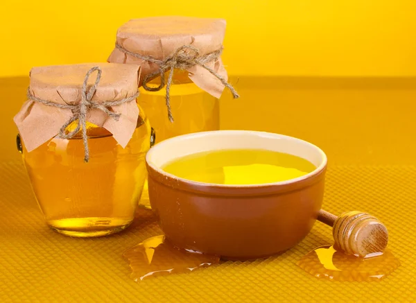 Guci madu, mangkuk dan kayu gerimis dengan madu di latar belakang sarang madu kuning — Stok Foto