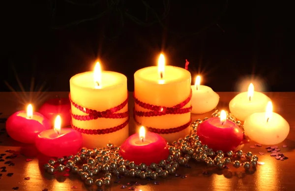 Schöne Kerzen und Dekor auf Holztisch auf schwarzem Hintergrund — Stockfoto