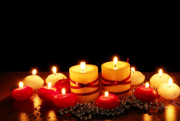 Piękne świece i wystrój na drewnianym stole na czarnym tle — Zdjęcie stockowe