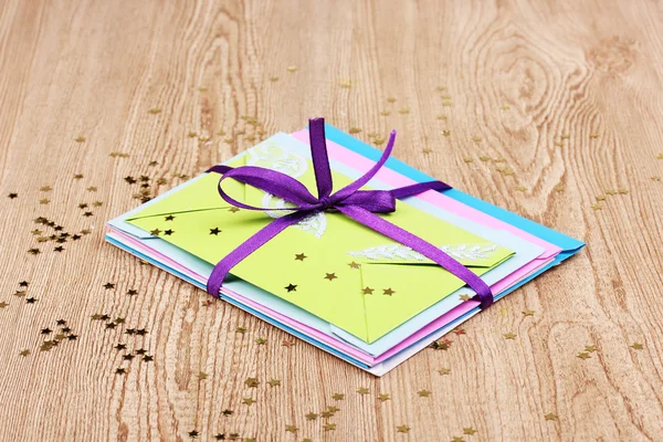 Manojo de sobres de color con cinta y confeti sobre fondo de madera —  Fotos de Stock