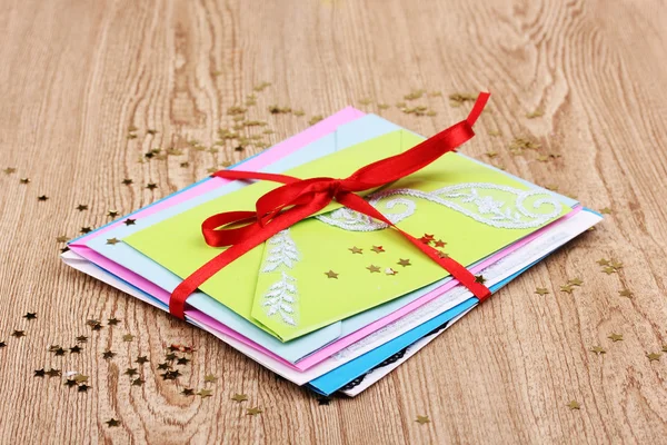 Група кольорових конвертів зі стрічкою та конфетті на дерев'яному фоні — стокове фото