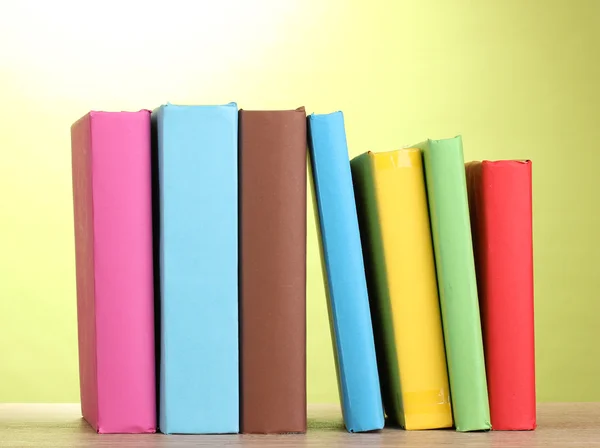 Boeken verblijf op houten tafel op groene achtergrond — Stockfoto
