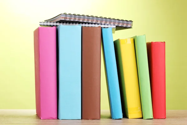 Knihy s šablonu na dřevěný stůl na zeleném pozadí — Stock fotografie