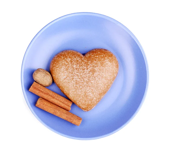 Biscuit en forme de coeur avec cannelle et noix de muscade sur soucoupe isolée sur blanc — Photo